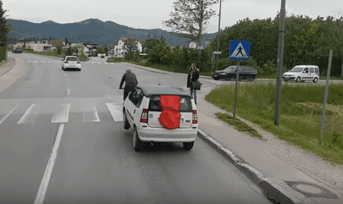 Un hombre remolca su coche con su bicicleta